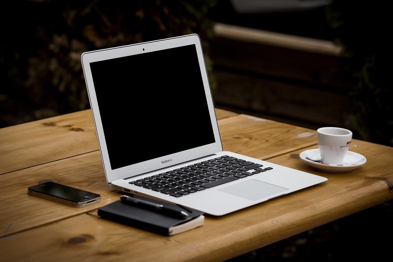 Laptop, phone, notebook, and coffee on a work table